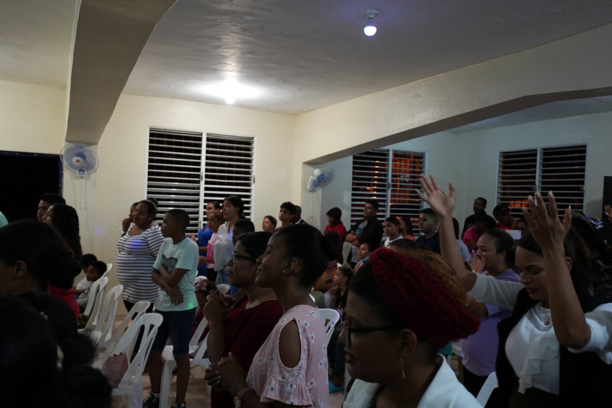 People standing together in a community hall, hands raised